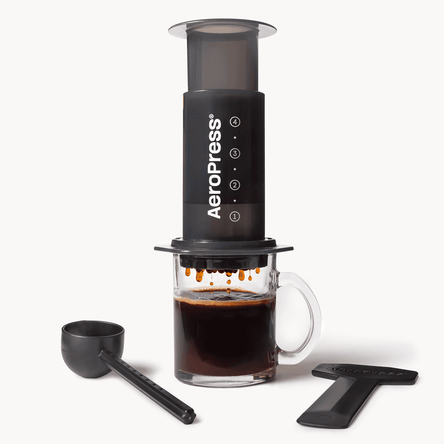AeroPress Original coffee maker in burgundy, with paper filters and a brewed cup